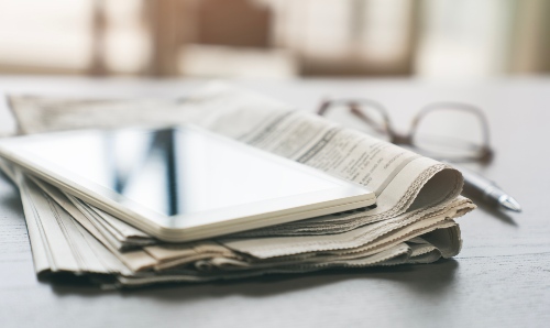 Newspapers and tablets on a table.